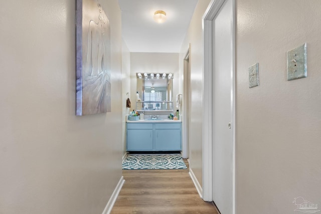 corridor featuring sink and light hardwood / wood-style flooring