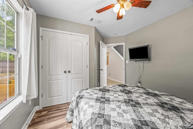 bedroom with visible vents, multiple windows, wood finished floors, and a closet