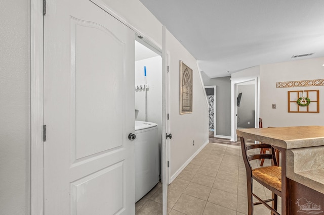 hallway featuring visible vents, baseboards, and light tile patterned floors