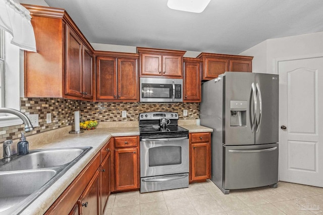 kitchen with decorative backsplash, light countertops, a sink, appliances with stainless steel finishes, and light tile patterned floors