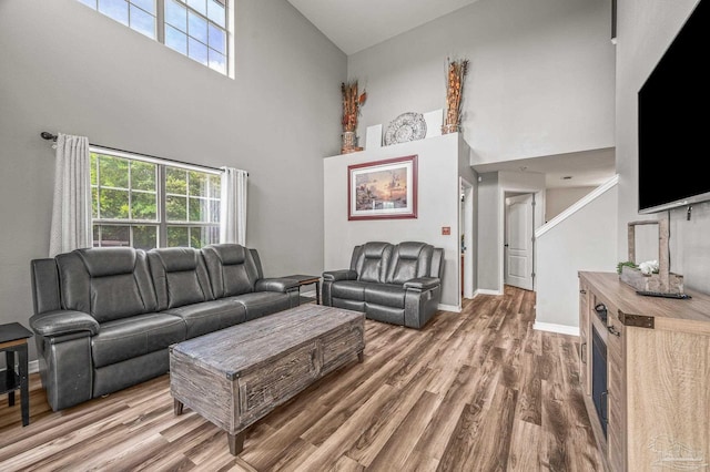 living area featuring baseboards, wood finished floors, a wealth of natural light, and high vaulted ceiling
