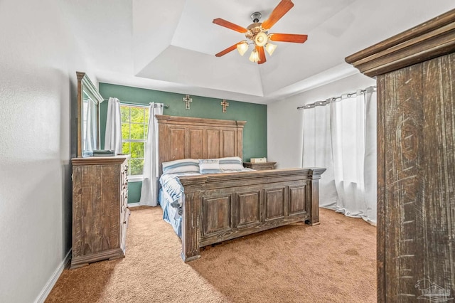 bedroom featuring baseboards, light carpet, ceiling fan, and a raised ceiling