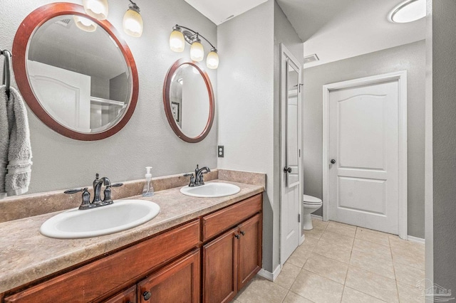 full bath with double vanity, a sink, tile patterned floors, and toilet