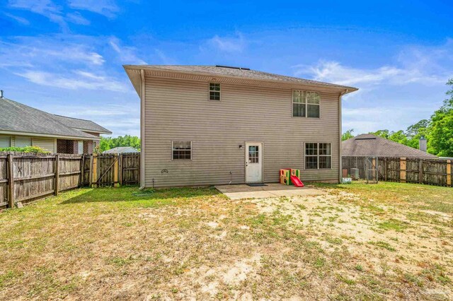 rear view of house featuring a yard, a patio, and a fenced backyard