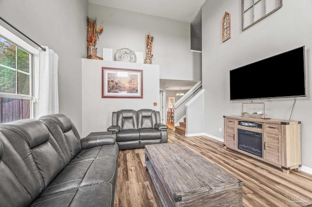 living room with stairs, baseboards, wood finished floors, and a fireplace