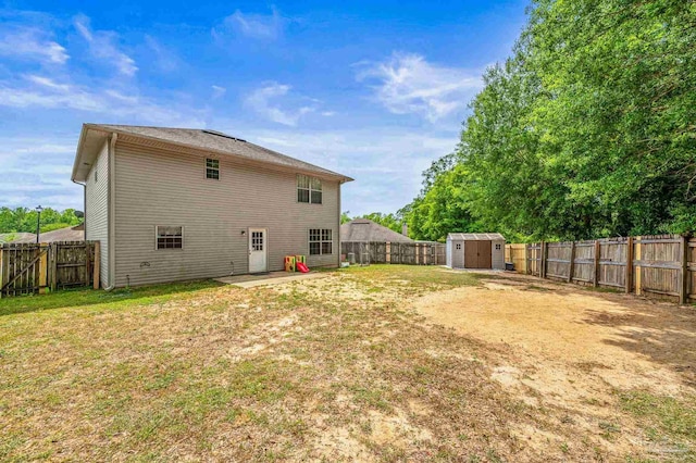 rear view of property featuring a yard, an outdoor structure, a shed, and a fenced backyard