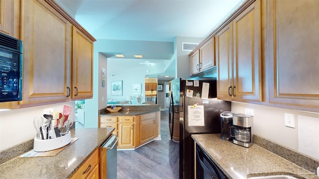 kitchen with stone countertops, black appliances, sink, and dark hardwood / wood-style floors