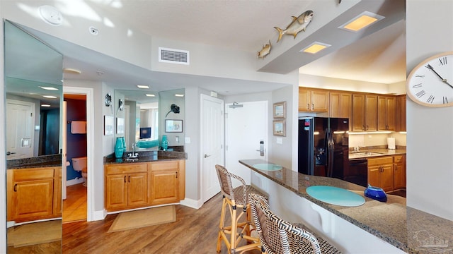 kitchen with sink, black appliances, dark hardwood / wood-style floors, and dark stone counters