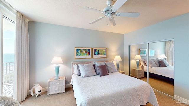 bedroom with a closet, light colored carpet, a water view, and ceiling fan