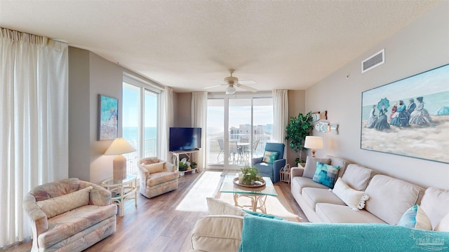 living room featuring light hardwood / wood-style floors, a textured ceiling, and ceiling fan