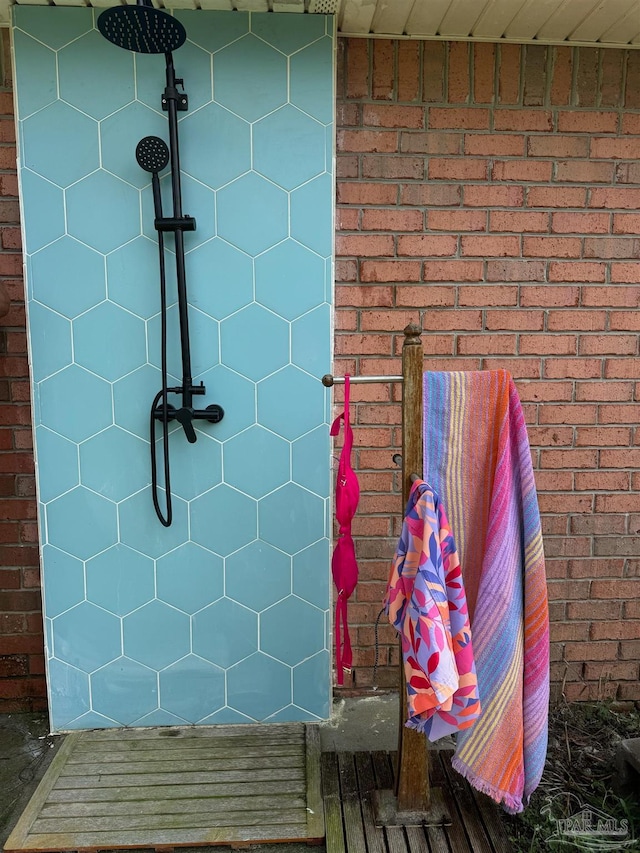 interior space with a shower and brick wall