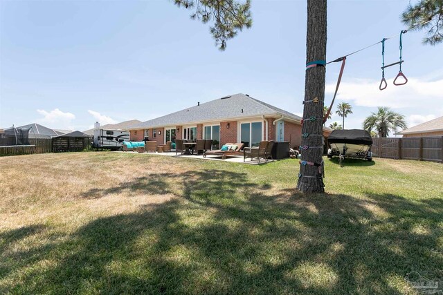 rear view of property featuring a yard, an outdoor hangout area, and a patio area