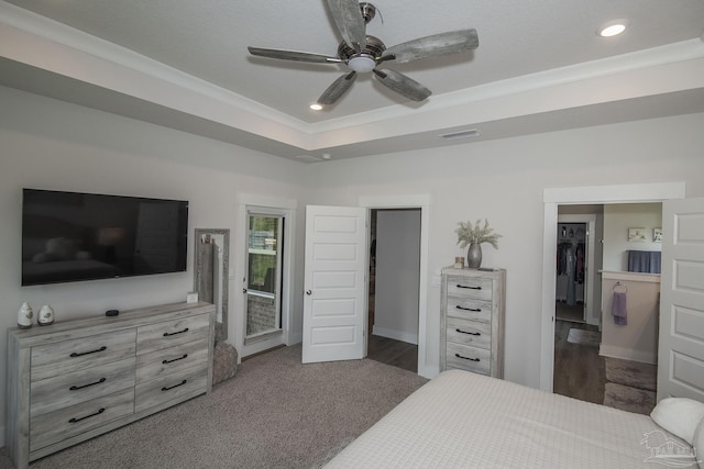 bedroom with a tray ceiling, a walk in closet, recessed lighting, visible vents, and a ceiling fan