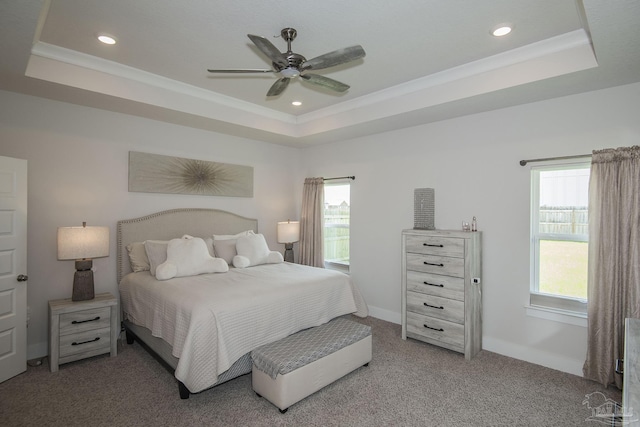 carpeted bedroom with baseboards, a tray ceiling, and ornamental molding