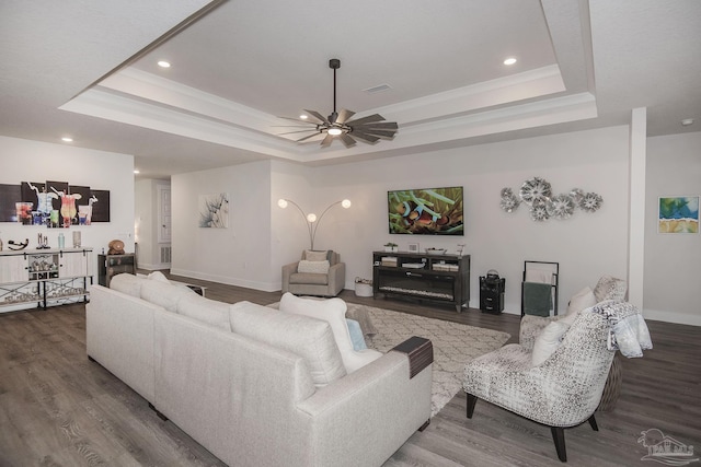 living room featuring baseboards, a tray ceiling, wood finished floors, and ornamental molding