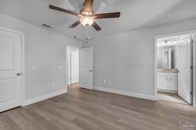 unfurnished bedroom with light wood-style flooring, a ceiling fan, visible vents, baseboards, and ensuite bath