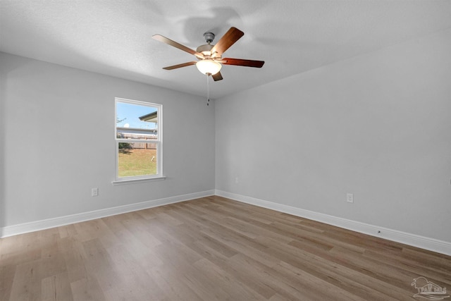 unfurnished room with light wood-style floors, ceiling fan, baseboards, and a textured ceiling