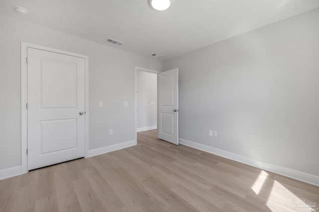 unfurnished bedroom with light wood-style flooring, visible vents, and baseboards