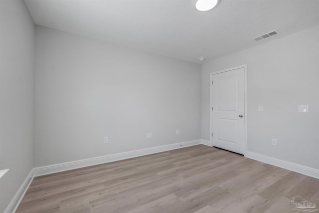 unfurnished room with light wood-type flooring, visible vents, and baseboards