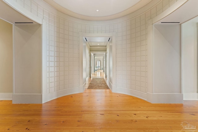 hall featuring tile walls, wood-type flooring, and ornamental molding