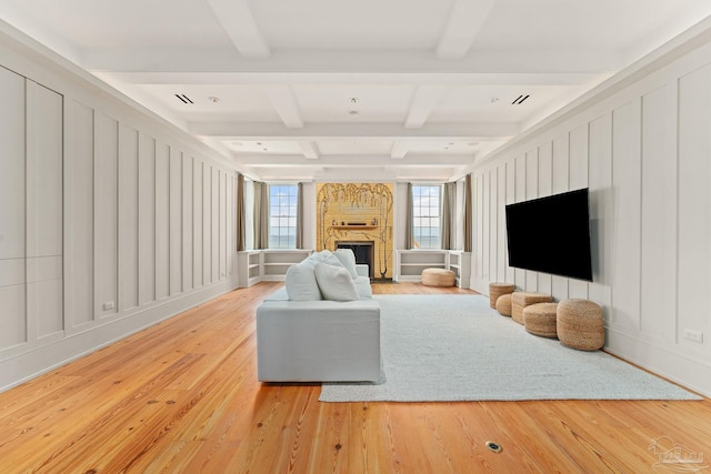 living room featuring coffered ceiling, hardwood / wood-style floors, beam ceiling, and a large fireplace