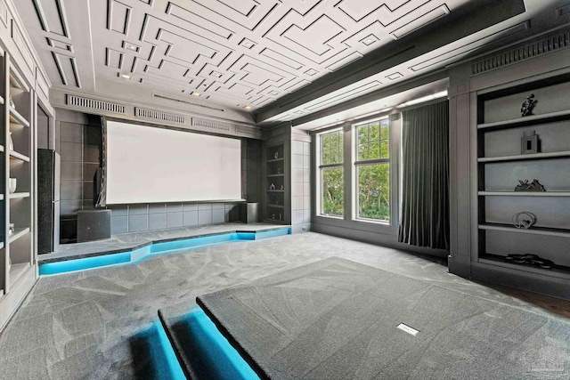 home theater room featuring built in shelves, ornamental molding, a tray ceiling, and carpet floors