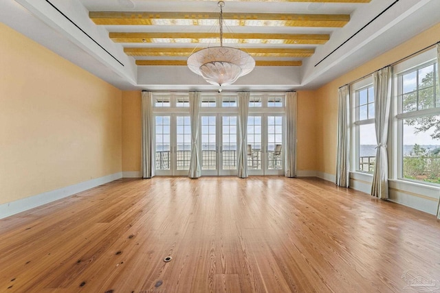 spare room with beamed ceiling and light wood-type flooring