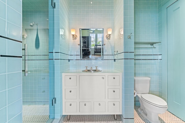 bathroom with tile walls, vanity, an enclosed shower, toilet, and tile patterned floors