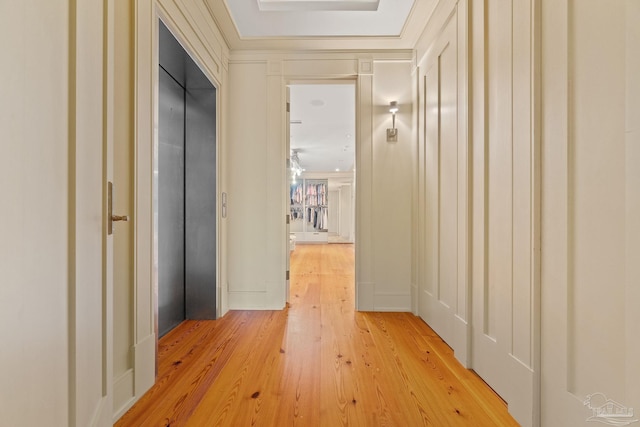 hallway with elevator, ornamental molding, and hardwood / wood-style floors