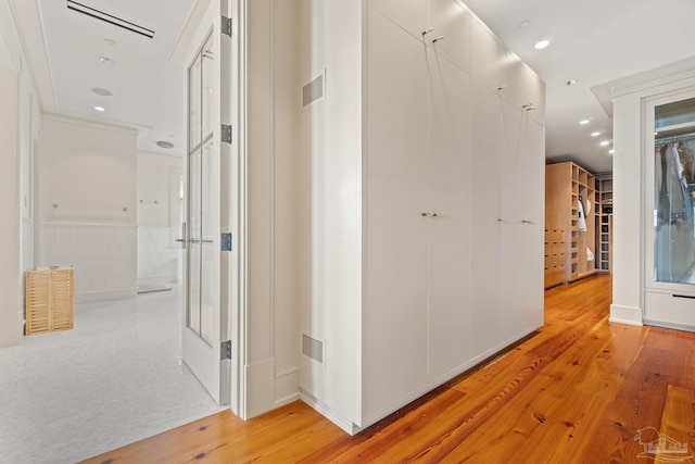 hall with crown molding and light hardwood / wood-style flooring