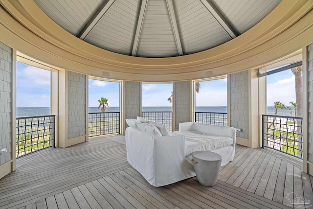 sunroom with lofted ceiling with beams and a water view