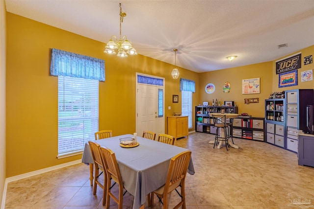 tiled dining room with a notable chandelier and a textured ceiling