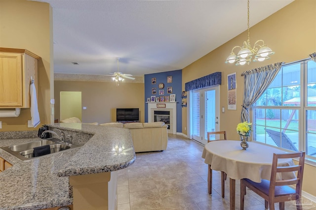 tiled dining room featuring ceiling fan with notable chandelier and sink