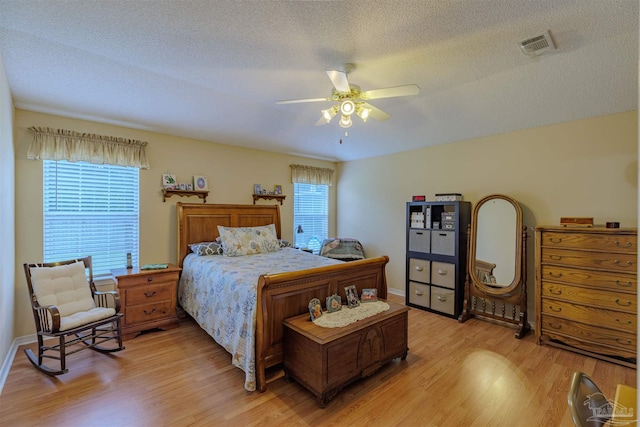 bedroom with ceiling fan, a textured ceiling, and light hardwood / wood-style floors