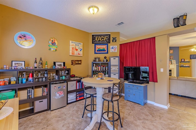 interior space with ceiling fan, a textured ceiling, and light tile patterned flooring