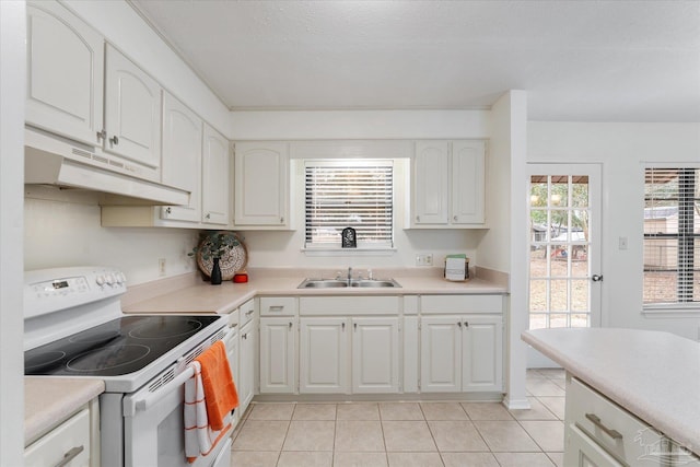 kitchen featuring white cabinetry, sink, light tile patterned flooring, and electric stove