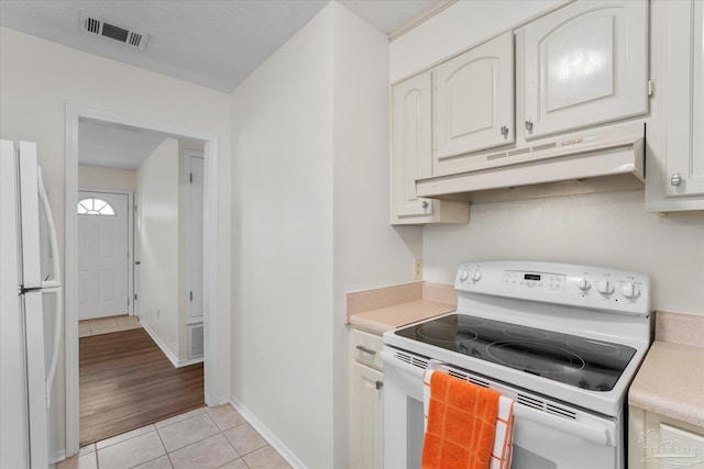 kitchen featuring light tile patterned floors, white appliances, a textured ceiling, and white cabinets