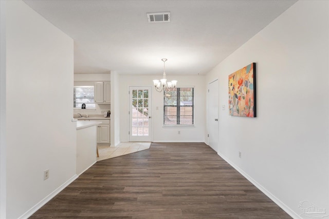 unfurnished dining area featuring an inviting chandelier and light wood-type flooring