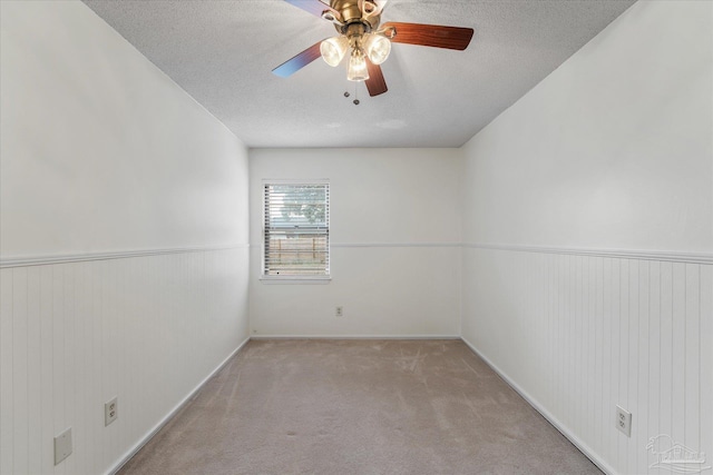 carpeted empty room with ceiling fan and a textured ceiling