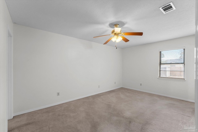 unfurnished room featuring ceiling fan, light colored carpet, and a textured ceiling