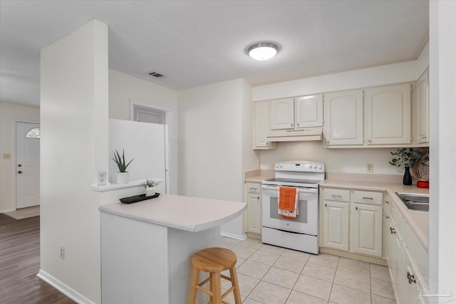 kitchen with sink, white appliances, a kitchen breakfast bar, light tile patterned flooring, and kitchen peninsula