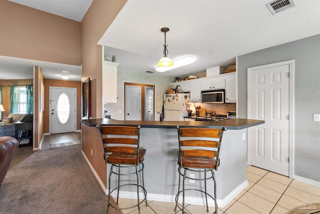917 Broken Arrow Ln, Pensacola, FL 32533 - kitchen featuring freestanding refrigerator, stainless steel microwave, dark countertops, a breakfast bar area, and white cabinets