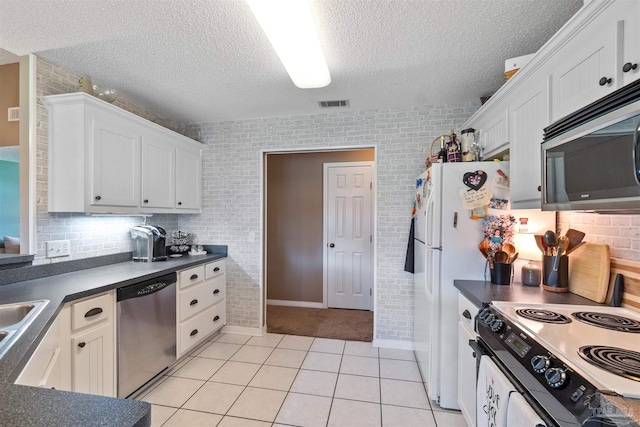917 Broken Arrow Ln, Pensacola, FL 32533 - kitchen featuring appliances with stainless steel finishes, dark countertops, a textured ceiling, white cabinetry, and brick wall