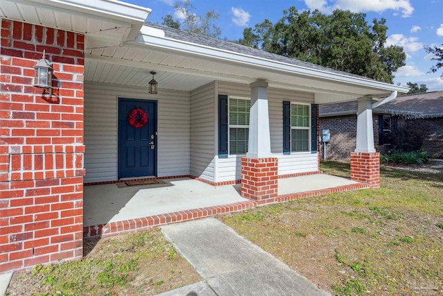 doorway to property with a lawn and a porch