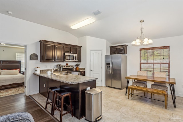 kitchen featuring kitchen peninsula, sink, appliances with stainless steel finishes, a notable chandelier, and dark brown cabinetry