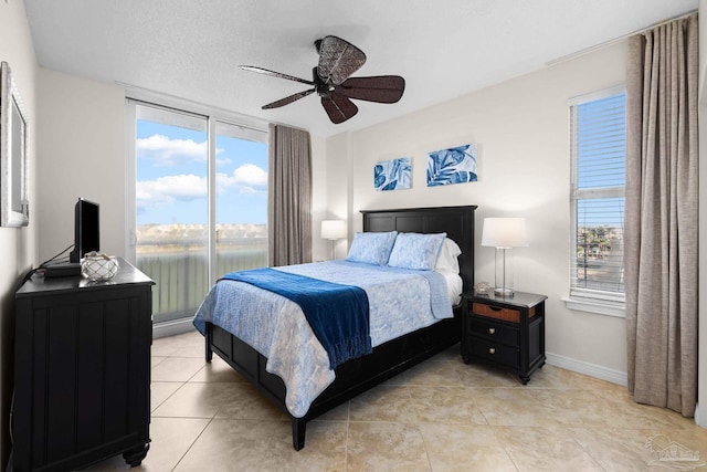 tiled bedroom featuring ceiling fan, a textured ceiling, and multiple windows