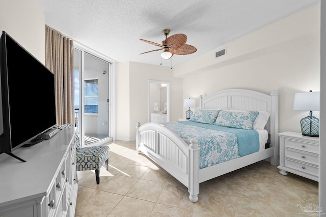 bedroom featuring ceiling fan, light tile patterned floors, and a textured ceiling