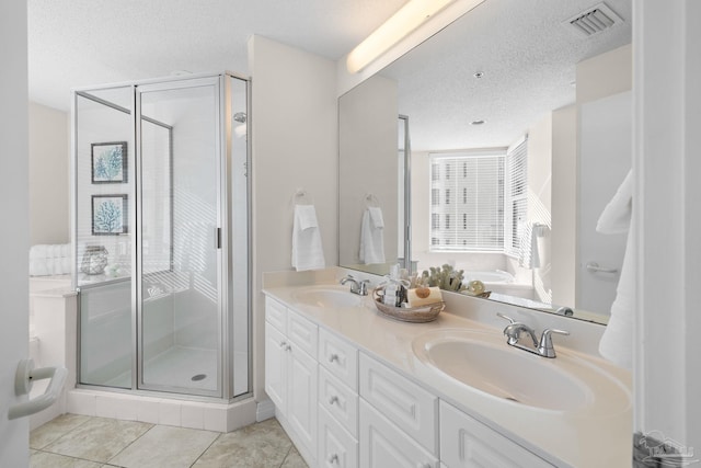 bathroom featuring tile patterned flooring, vanity, a shower with shower door, and a textured ceiling