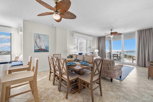 tiled dining area with a textured ceiling, a water view, and ceiling fan