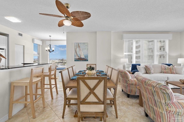 tiled dining area with ceiling fan with notable chandelier and a textured ceiling